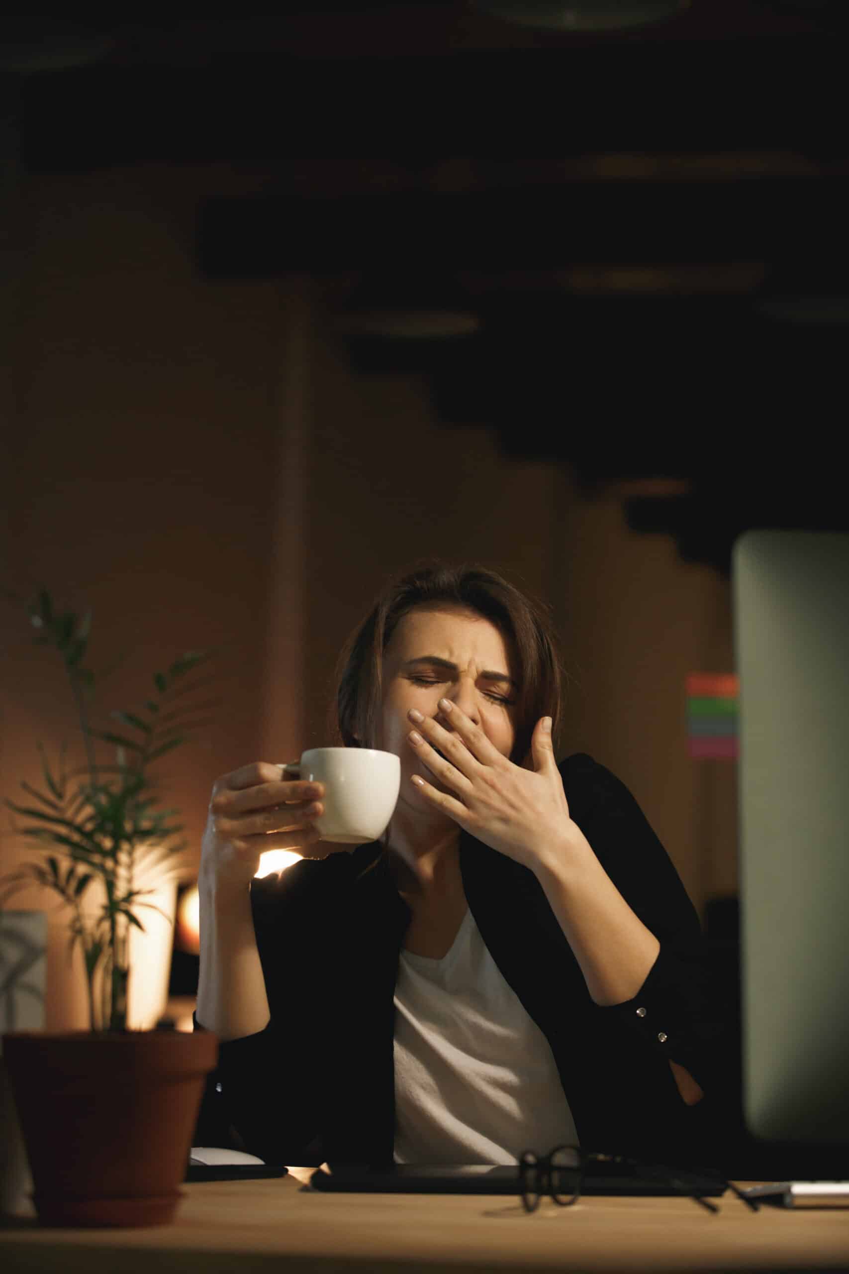 Yawning young woman designer sitting indoors